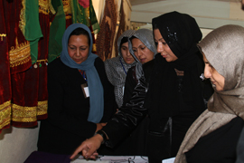 La directora del Parque de Maquinaria de Qala i Naw y la secretaria del Consejo Provincial de Badghis, entre otras, contemplan una exposición de productos de la provincia