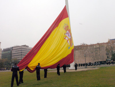 Un grupo de marineros  izando  la Bandera en la plaza del descubrimiento, durante el acto, una unidad de la Armada española rinde honores.