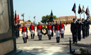 Miembros de la Guardia Civil colocan una corona ante el monolito en homenage a los caídos, acompañados por guiones y banderines.