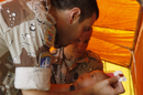 Militares del equipo médico español atendiendo a un niño en el consultorio del destacamento de Qala i Naw (Afganistán)