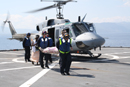 Soldados españoles transportan una camilla junto a un helicóptero de la Armada
