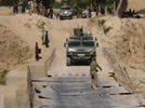 Vehículos militares españoles Vamtac, se disponen a cruzar el único puente viable de la zona.