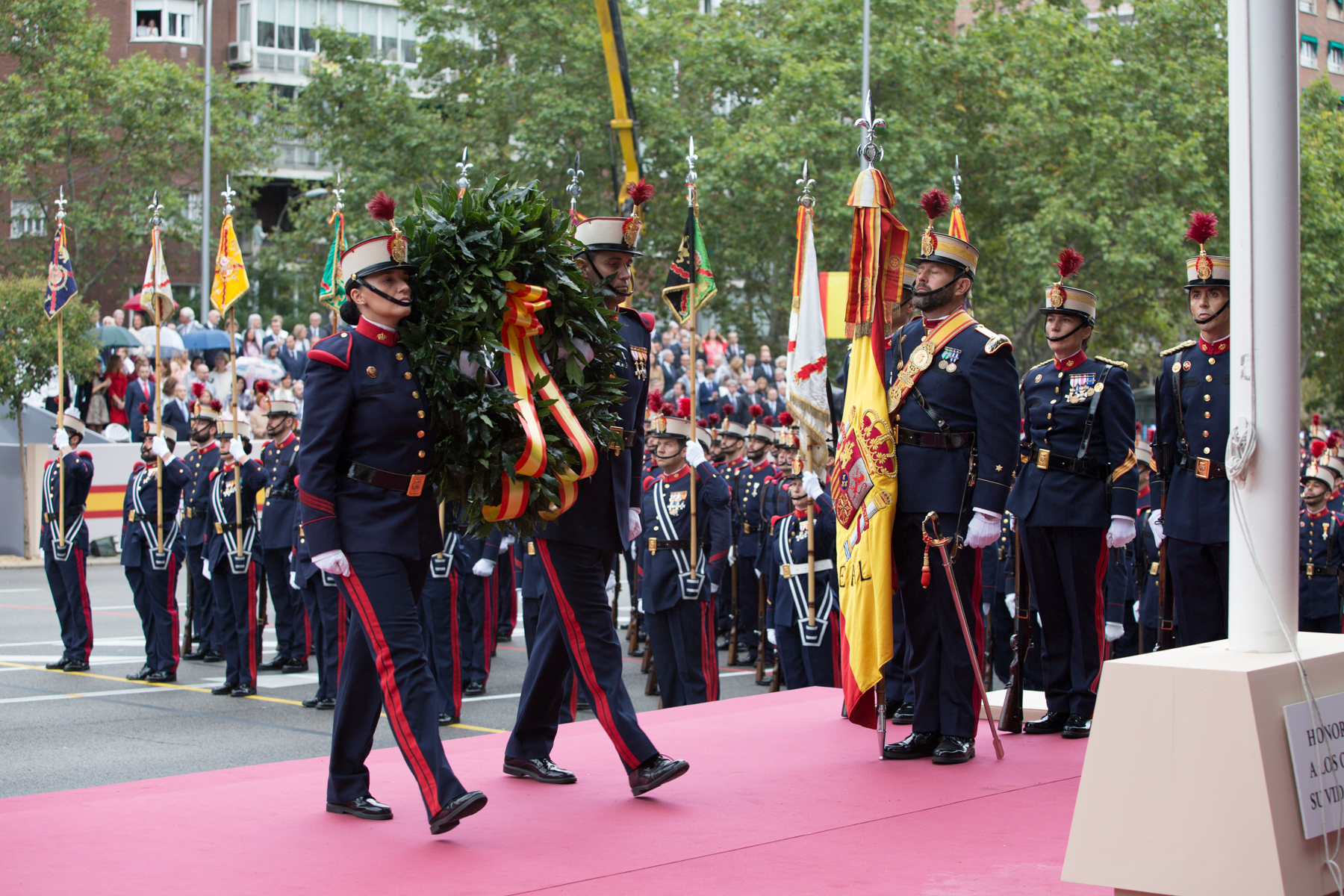 Dos guardias reales portan la corona de laurel durante el Acto a los caidos por España