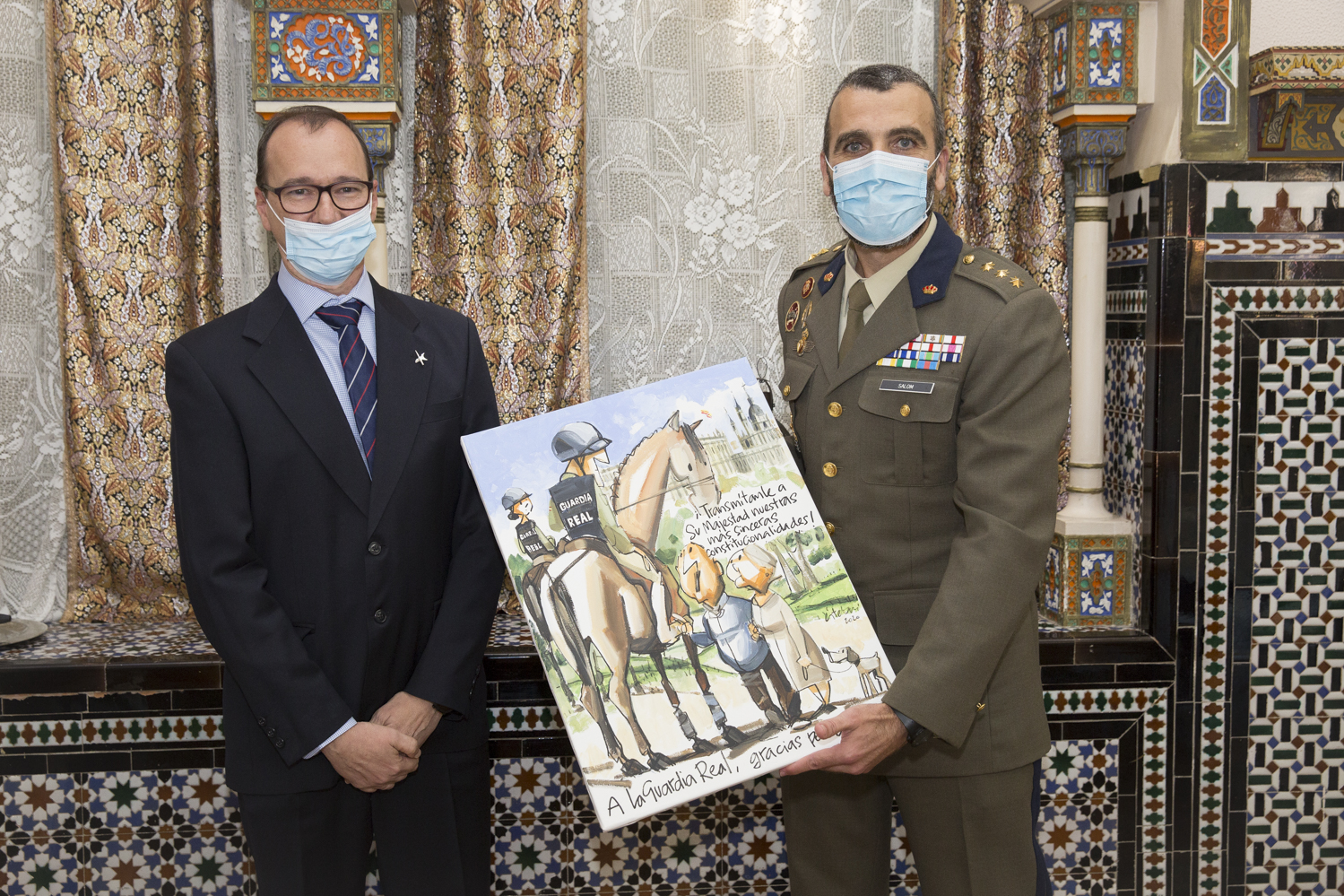 El coronel jefe de la Guardia Real recibe de manos del humorista gráfico Esteban una de sus viñetas