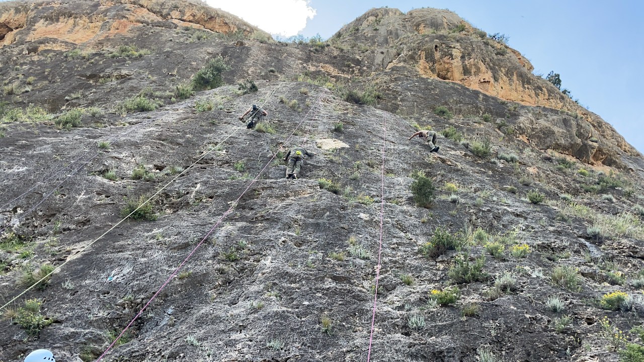 Monteros trepando por una pared en sus prácticas de montaña