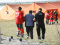 Miembros de la UME y la Cruz Roja , acompañan a uno de los figurantes al campamento de damnificados