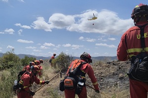 Miembros de la UME apoyados por un helicoptero de extinción de incendios.